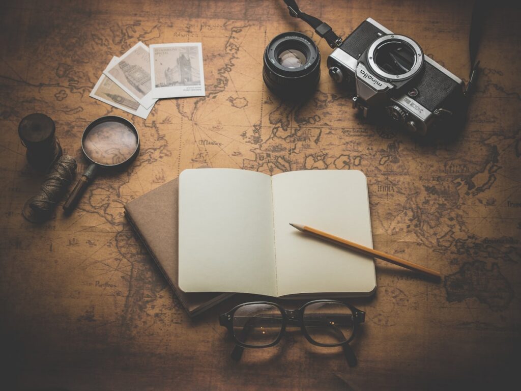Notebook, vintage camera and map on a desk for planning a trip